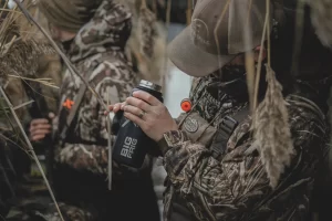 man holding 30 oz tumbler while hunting